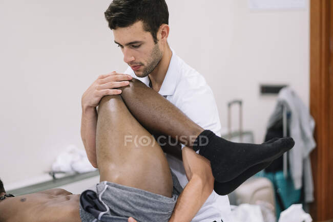 El fisioterapeuta que trata a un hombre usando equipos para radioterapia - foto de stock