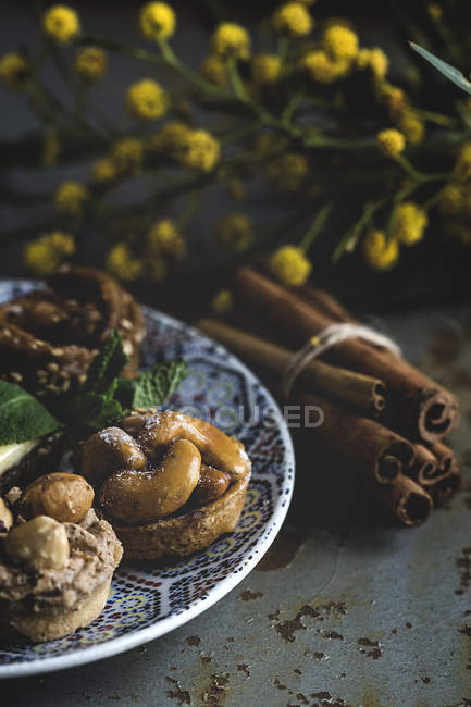 Dulces típicos marroquíes con miel y almendras en el plato en la superficie de mala calidad con palitos de canela - foto de stock