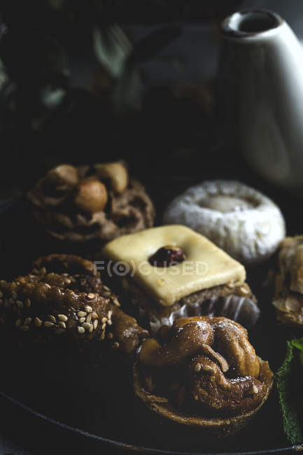 Gros plan des bonbons marocains typiques avec du miel et des amandes sur plaque sur fond sombre — Photo de stock