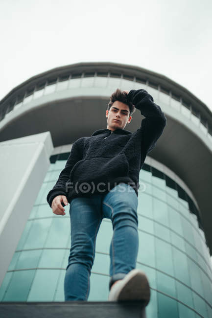 Молодий чоловік стоїть на тлі сучасного будинку — стокове фото
