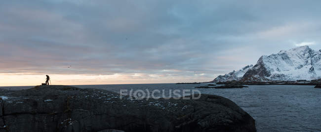 Vue pittoresque sur les montagnes enneigées en mer avec silhouette de touriste sur fond — Photo de stock