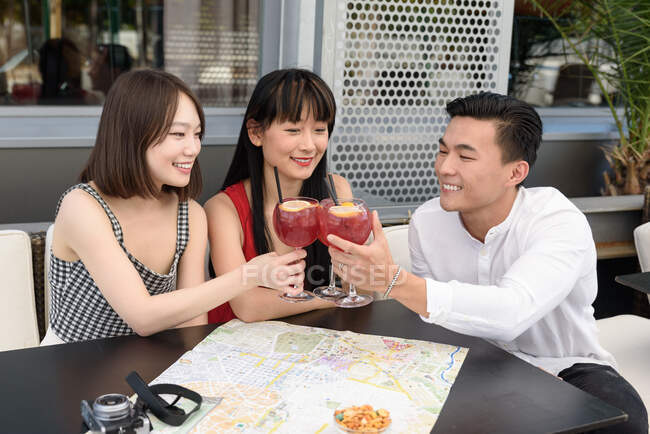 Asian tourists clinking glasses in cafe — Stock Photo