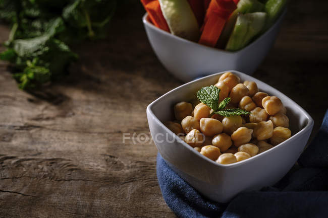 Boiled chickpeas in bowl on rustic wooden table — Stock Photo