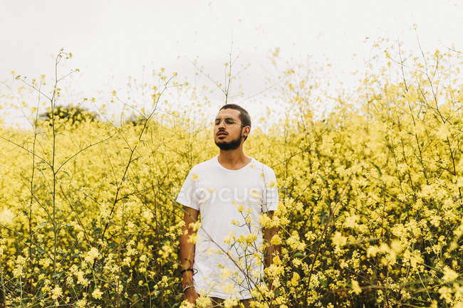 Mann steht zwischen gelben Blumen — Stockfoto