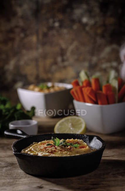 Homemade chickpea humus on wooden table with ingredients — Stock Photo