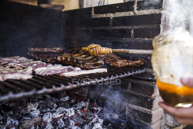 Hand des Barbecue-Managers einweichen Sauce mit Schweinerippchen mit Stock — Stockfoto