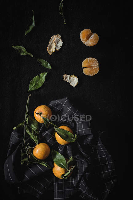 Tangerinas maduras frescas com folhas verdes sobre fundo preto — Fotografia de Stock