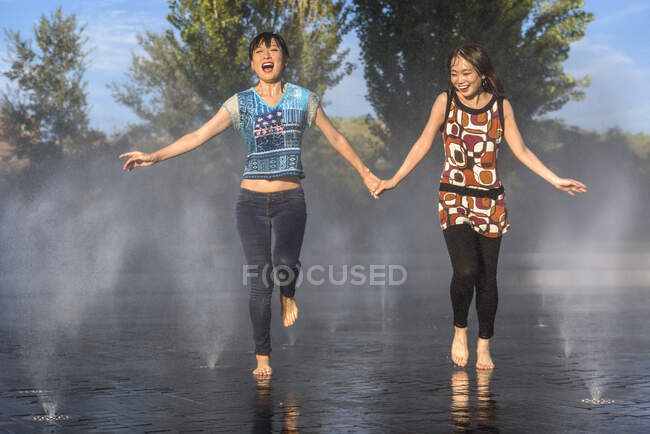 Asiatico donne jumping su fontana acqua — Foto stock