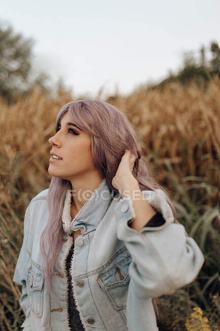 Side view of beautiful modern woman with pink hair smoking cigarette with eyes closed in autumnal nature — Stock Photo