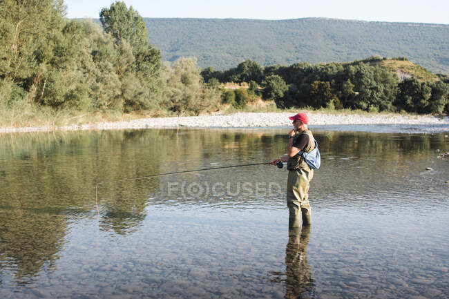 Uomo in piedi in acqua e pesca — Foto stock