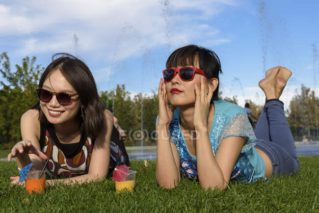 Asian women lying on park grass — Stock Photo