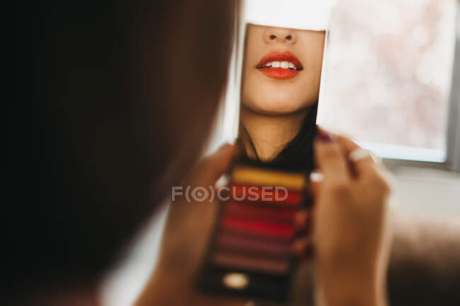 Отражение молодой женщины с карманным зеркалом и нанесение макияжа дома — стоковое фото