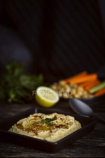 Húmus de grão de bico caseiro em mesa de madeira com ingredientes — Fotografia de Stock