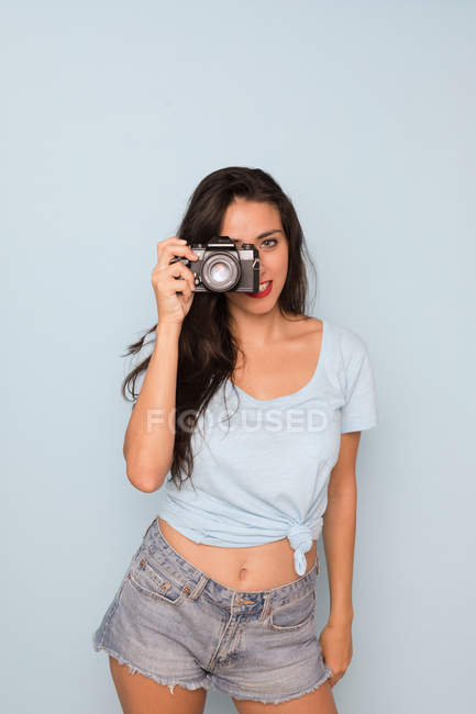 Молодая женщина в футболке и джинсовых шортах снимает на камеру — стоковое фото