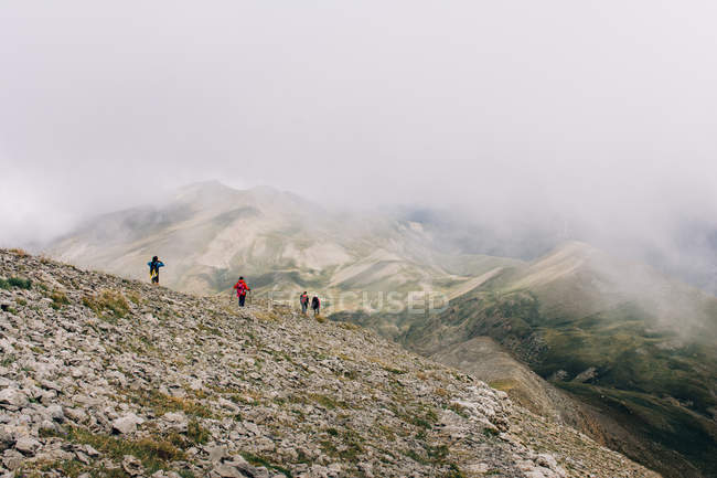 Группа путешественников, идущих вдоль горного хребта в туманный день — стоковое фото