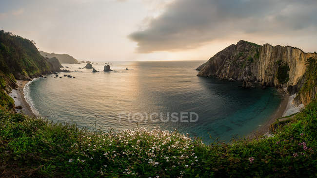 Herrliche runde Meeresbucht bei Sonnenuntergang am bewölkten Abend, Asturien, Spanien — Stockfoto
