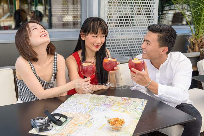 Los turistas asiáticos tintineo vasos en la cafetería - foto de stock