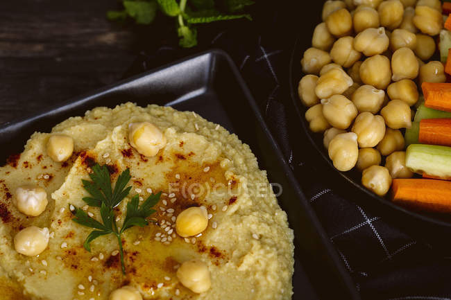 Húmus de grão de bico caseiro com pepino e cenoura em mesa de madeira — Fotografia de Stock