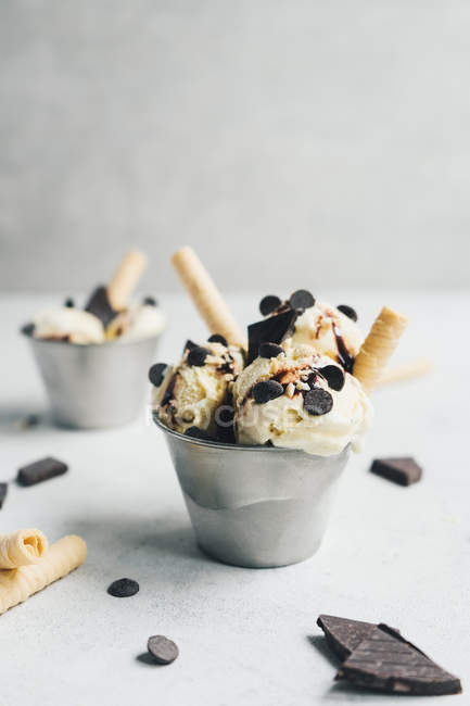 Ванильное мороженое с шоколадом и вафлями в маленьком ведре на белом столе — стоковое фото