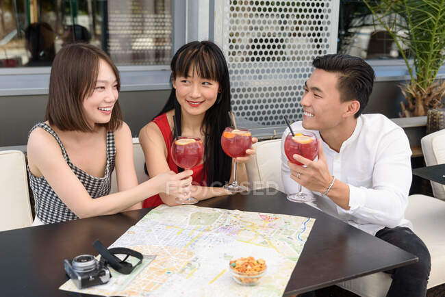 Los turistas asiáticos tintineo vasos en la cafetería - foto de stock