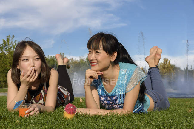 Asian women lying on park grass — Stock Photo