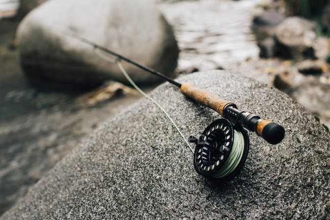 Close-up of fishing rod on smooth boulder on shore in nature — Stock Photo