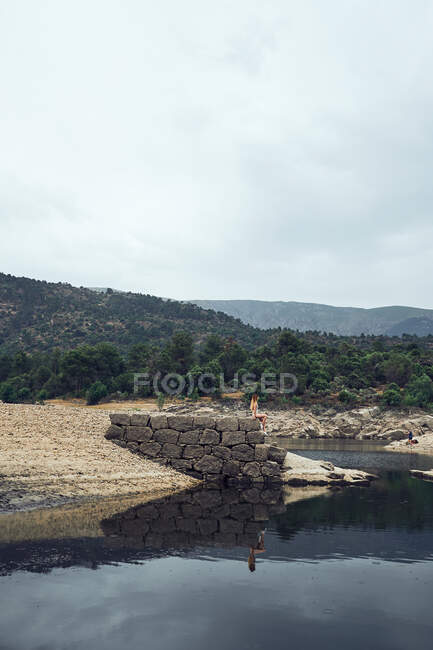 Jovem mulher de pé na rocha perto da água — Fotografia de Stock