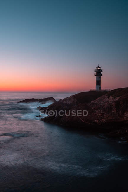 Beacon on sea coast during majestic sunset in cloudless evening, Asturias, Spain — Stock Photo