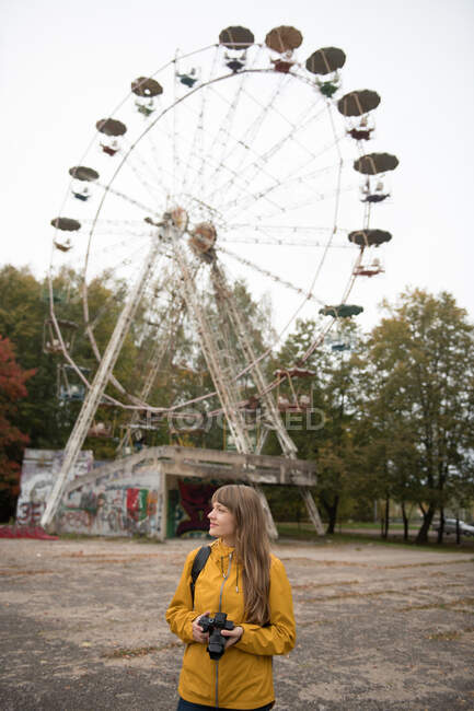 Visão traseira da mulher loira com câmera tirando foto do parque de diversões desolado com atrações — Fotografia de Stock