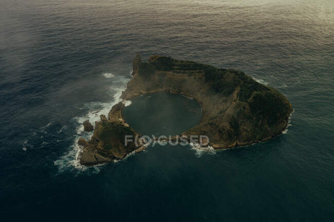 Aerial view of rocky island in blue quiet sea at daylight — Stock Photo