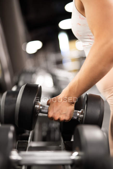 Close-up of female hand taking iron dumbbell for workout in gym — Stock Photo