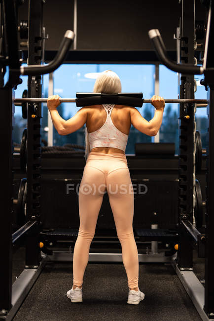 Жінка займається вправами з штангою в спортзалі — стокове фото