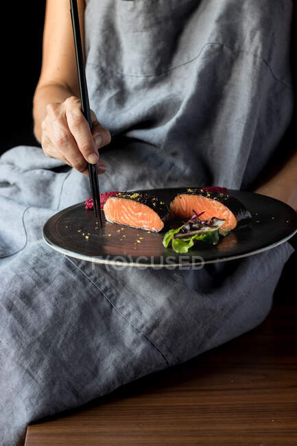 Femme parlant de délicieux filets de saumon avec des baguettes — Photo de stock