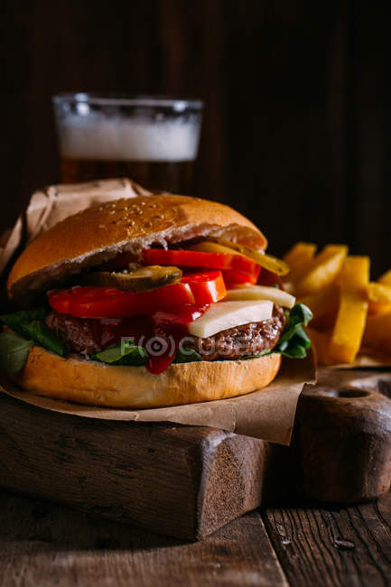 Delicious gourmet burger on dark wooden background — Stock Photo