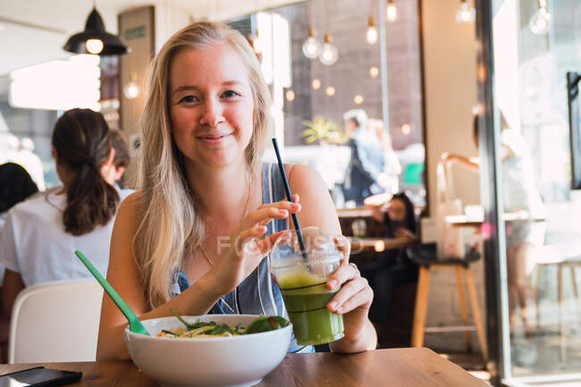 Femme prenant un verre et un repas dans un café — Photo de stock