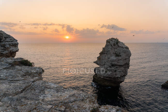 Rochas ásperas incríveis em pé na água do mar calma durante o belo pôr do sol em Tyulenovo, Bulgária — Fotografia de Stock
