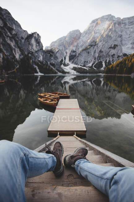 Legs of anonymous man lying on steps near pier and calm surface of Pragser Wildsee in Dolomites, Italy — Stock Photo