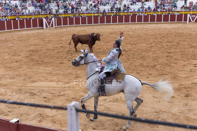 Испания, Томеллосо - 28. 08. 08 2018 год. Вид женщины-быка верхом на лошади и бой с быком на песчаной площади с людьми на трибунах — стоковое фото