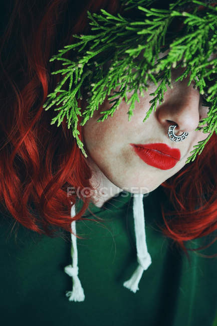 Jovem mulher ruiva cobrindo os olhos com galho de abeto verde — Fotografia de Stock