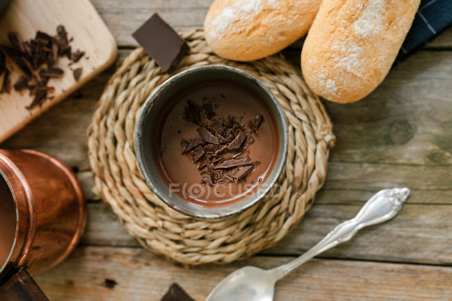 Taza de chocolate caliente con trozos de chocolate cubriendo la mesa de madera - foto de stock