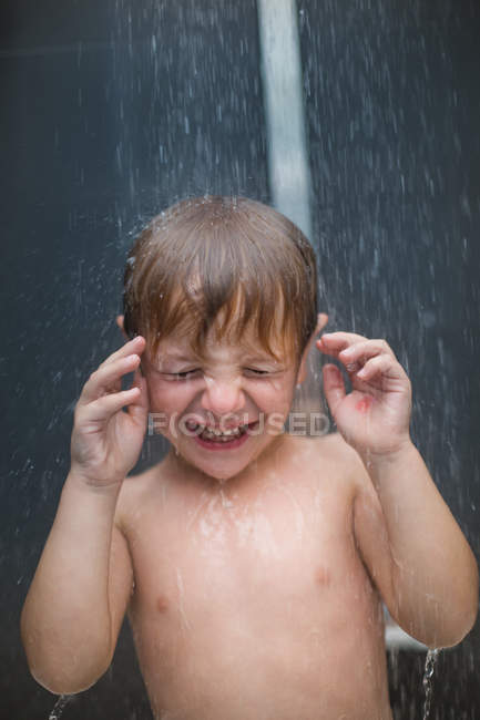 Kaukasischer Junge spielt mit Wasser in der Dusche — Stockfoto