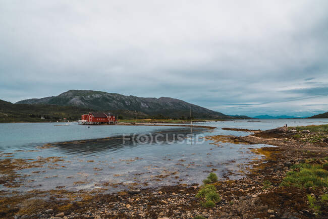 Quay with wooden house near high mountain — Stock Photo