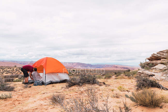 Traveler packing backpack and closing tent — Stock Photo
