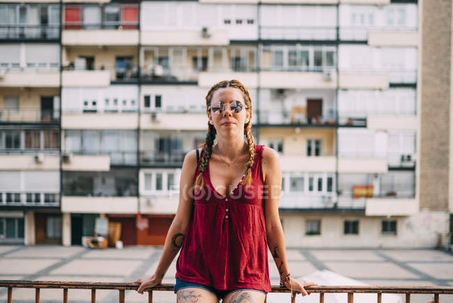 Hübsches rothaariges Mädchen mit Zöpfen und Sonnenbrille lehnt an Geländer an Wohnhaus — Stockfoto