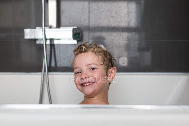 Portrait of smiling little boy sitting in bath — Stock Photo