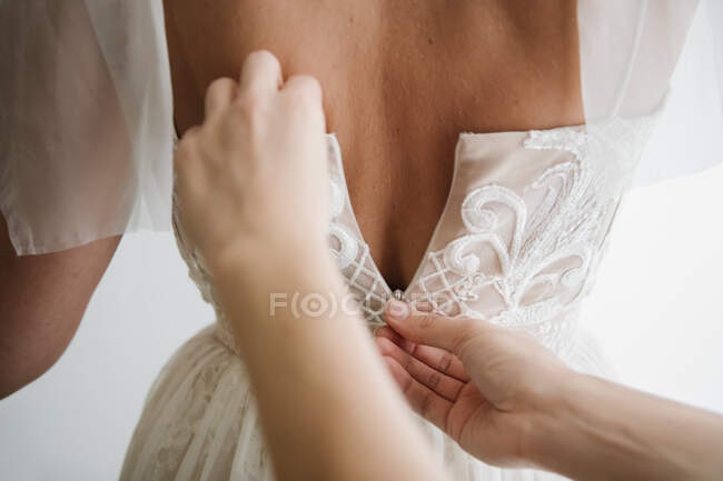 Mãos de colheita de pessoa ajudando a noiva a zip vestido branco — Fotografia de Stock