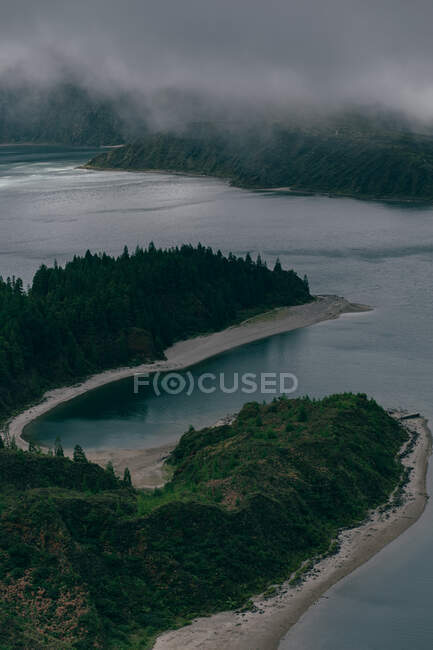 Dall'alto vista del lago blu pulito circondato da colline con nebbia grigia sopra — Foto stock