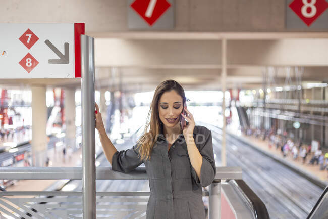 Жінка розмовляє на смартфоні на залізничній станції — стокове фото