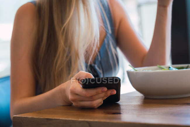 Жінка переглядає смартфон у кафе — стокове фото