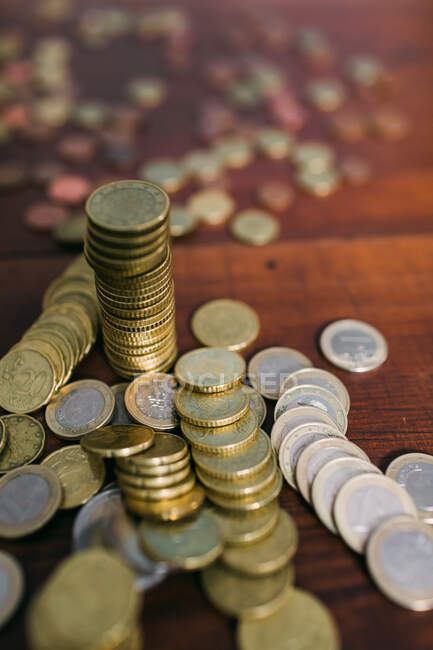 Крупним планом знімок купи і стопки дрібних монет, що лежать на дерев'яній стільниці — стокове фото